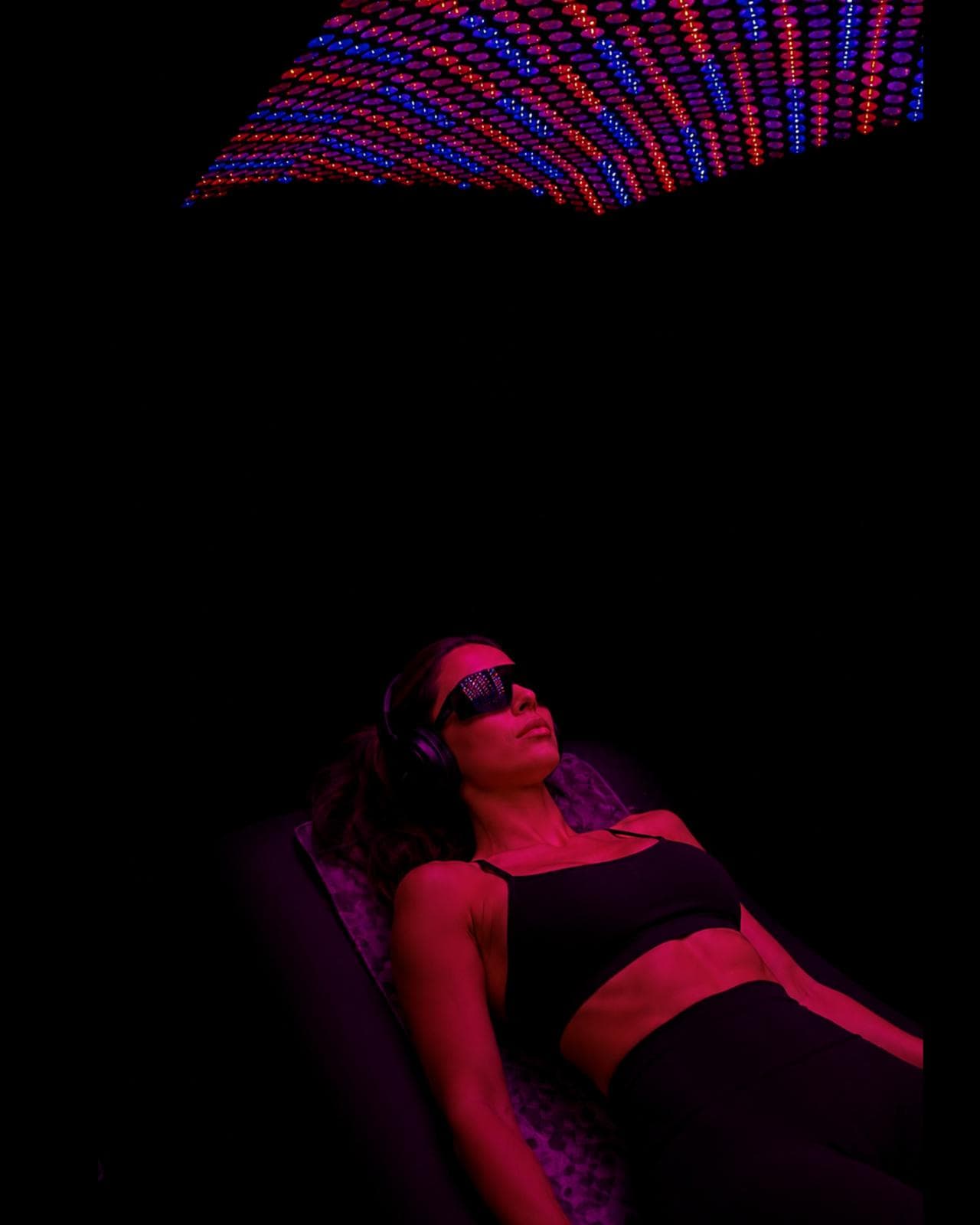 Woman relaxing under Powerhouse Trio red and blue light therapy at Eleve Newport Beach